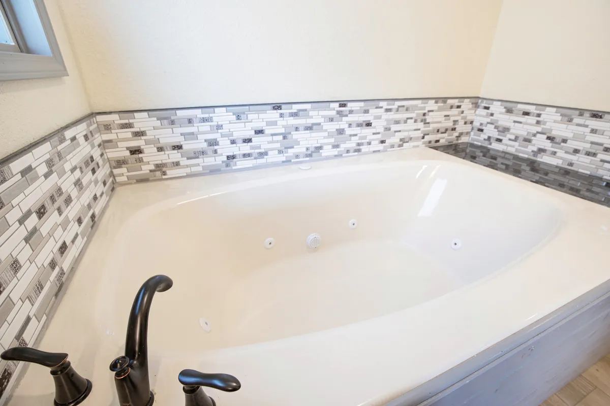 A tranquil bathroom scene featuring a standalone bathtub with a sleek faucet and decorative tile backdrop. The space is styled for relaxation, suggesting spa-like experiences perfect for unwinding in privacy after a day of adventure.