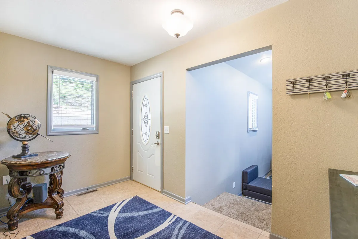 This image captures the entryway, featuring a welcoming front door, a decorative globe on a table, and a patterned rug. The space is inviting and organized, conveying the home's first impression to arriving guests.