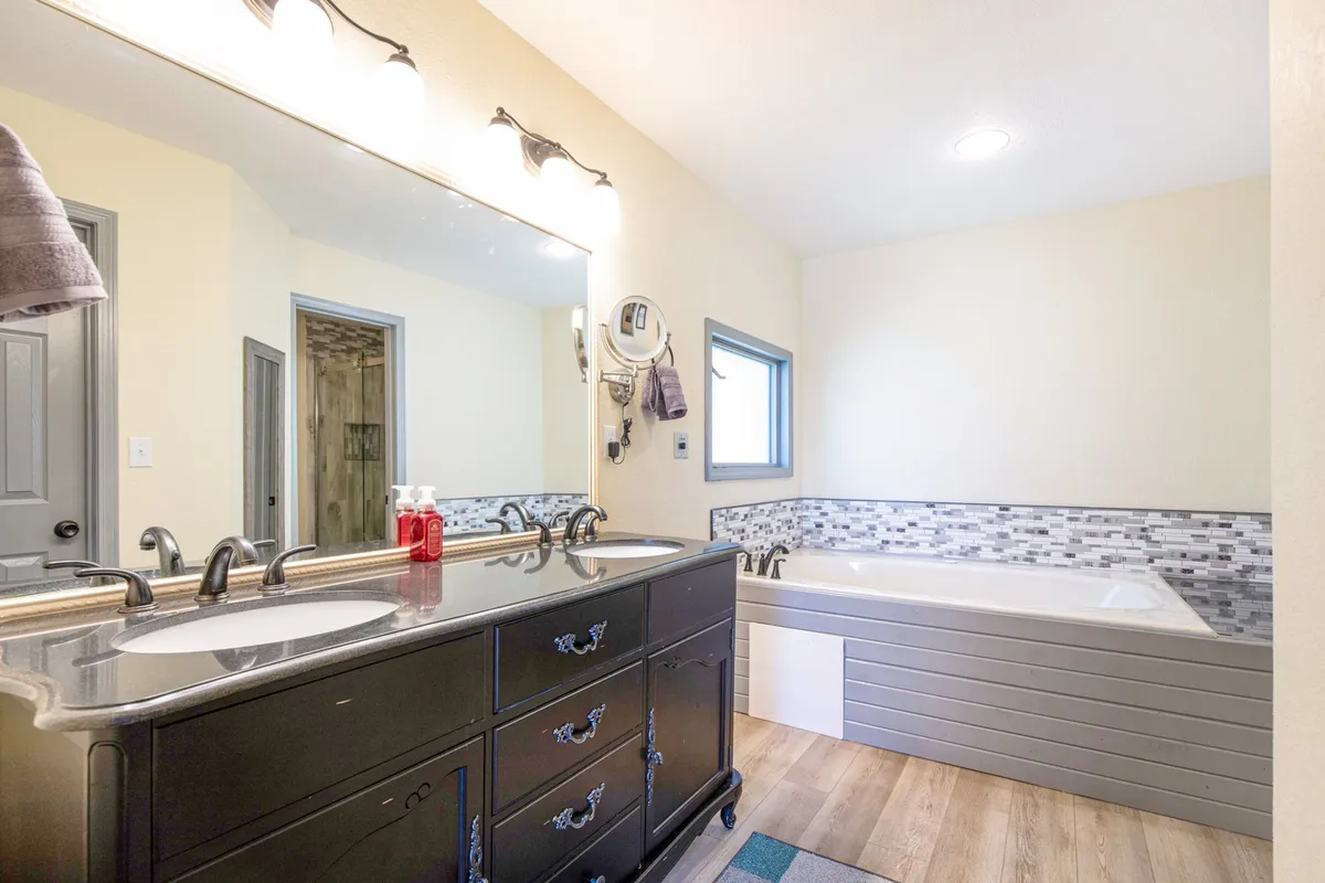 A spacious bathroom with dual sinks, a freestanding bathtub, and a mirrored vanity bathed in natural light. The design is serene and elegant, inviting guests to refresh and enjoy moments of self-care.