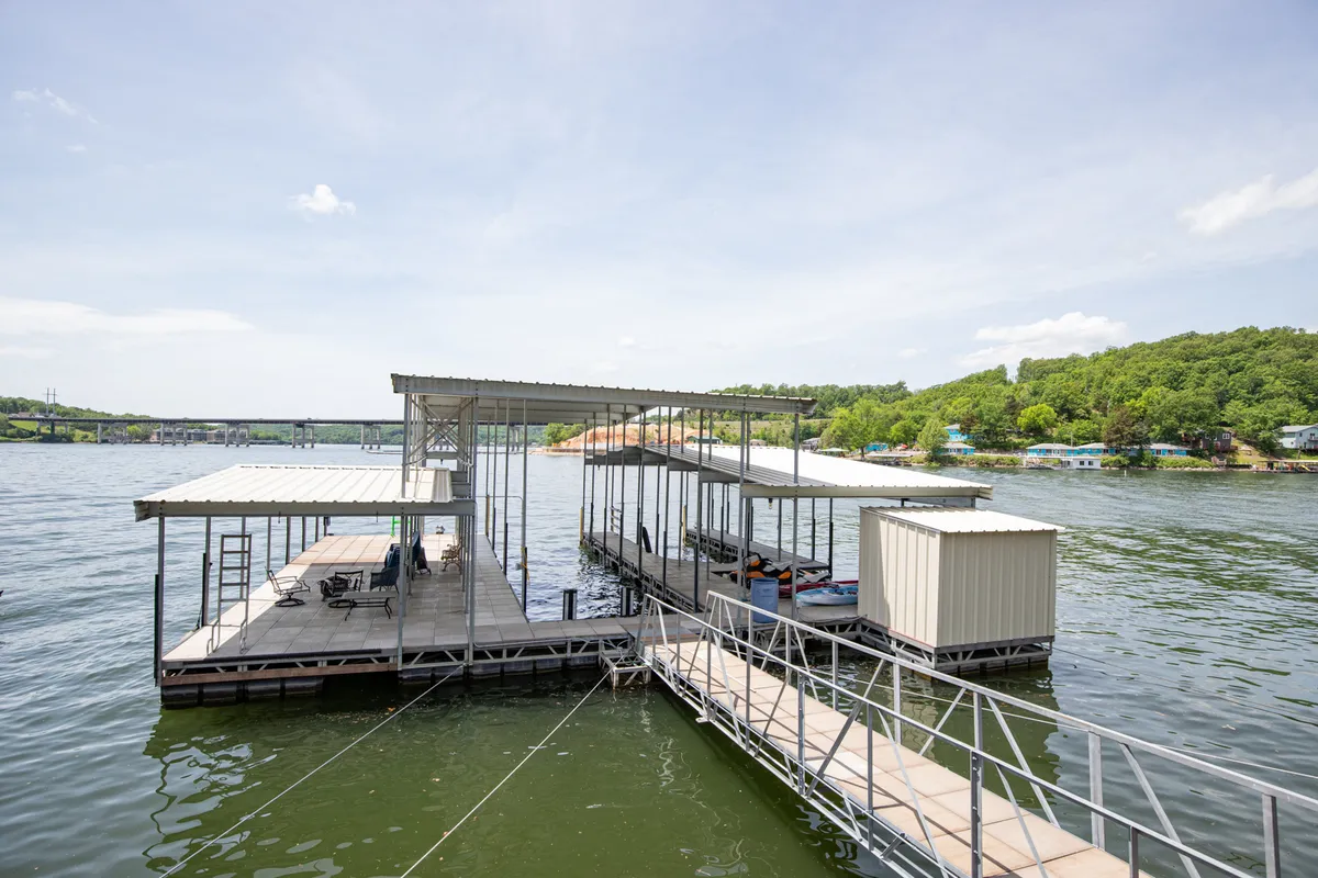 A serene view of the floating dock stretching out over the water, surrounded by lush green hills. The dock is an inviting launch point for boating, fishing, or simply relaxing by the shore, representing a key hub for year-round adventure.